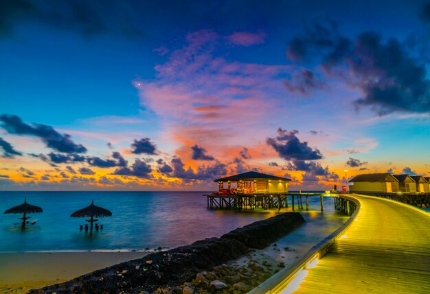Hermosas villas de agua en la isla tropical de Maldivas en la puesta del sol tiempo