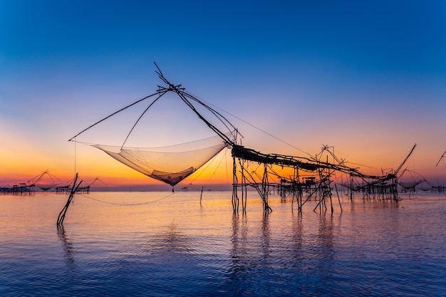 Hermoso amanecer y redes de inmersión de pesca en Pakpra en Phatthalung, Tailandia.
