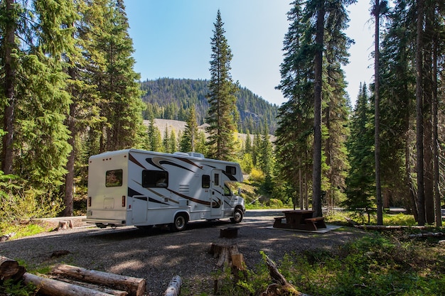 Hermoso camping en las montañas con una casa rodante y un banco de madera.