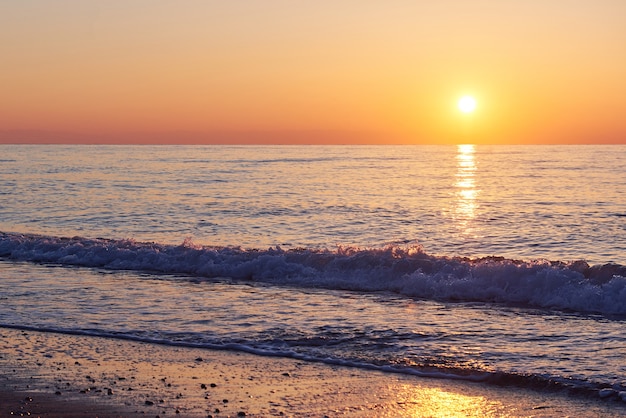 Hermoso colorido atardecer sobre el mar y el sol brilla. Cielo naranja.