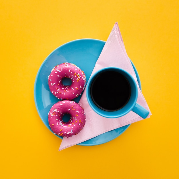 Foto gratuita hermoso desayuno con donas y una taza de café en amarillo