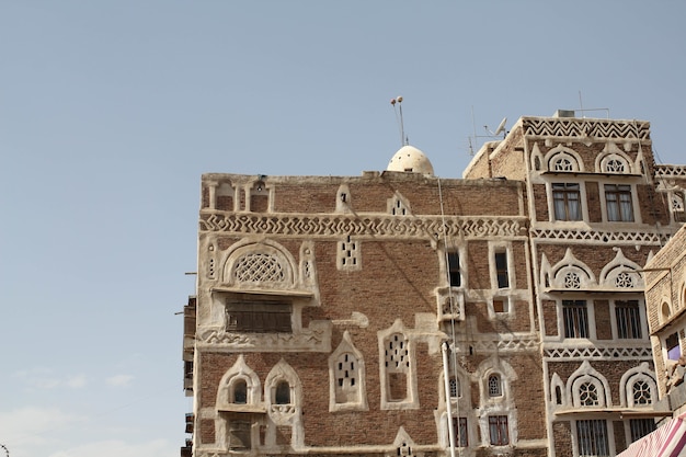 Hermoso edificio antiguo bajo la luz del sol y un cielo azul en Sana'a, Yemen
