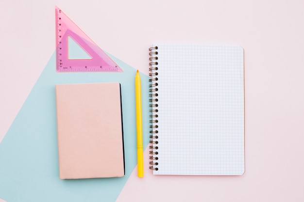 hermoso escritorio con cuaderno y regla sobre fondo rosa