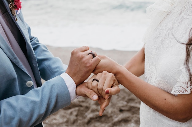 Hermoso esposo y esposa posando en la playa en su boda