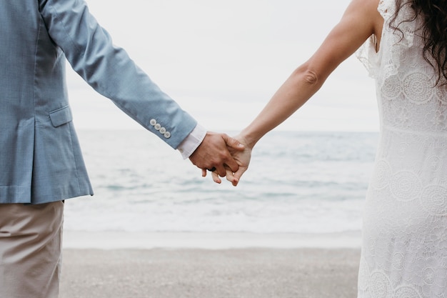 Foto gratuita hermoso esposo y esposa posando en la playa en su boda