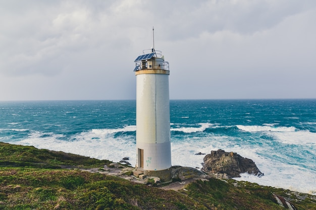 Hermoso faro en los acantilados con el magnífico mar tempestuoso