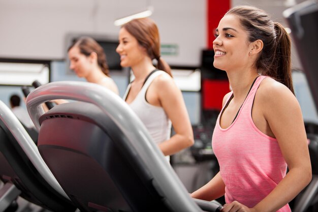 Hermoso grupo de mujeres jóvenes haciendo ejercicio en una caminadora en el gimnasio