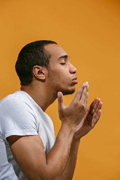 Hermoso hombre afroamericano está haciendo beso aéreo contra el espacio naranja