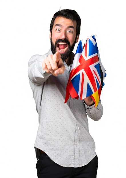 Foto gratuita hermoso hombre con barba sosteniendo muchas banderas y apuntando hacia el frente