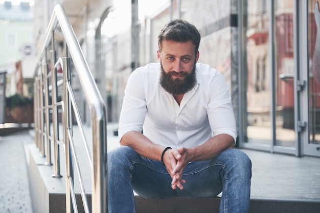 Foto gratuita un hermoso hombre barbudo con ropa de diario mira a la cámara.