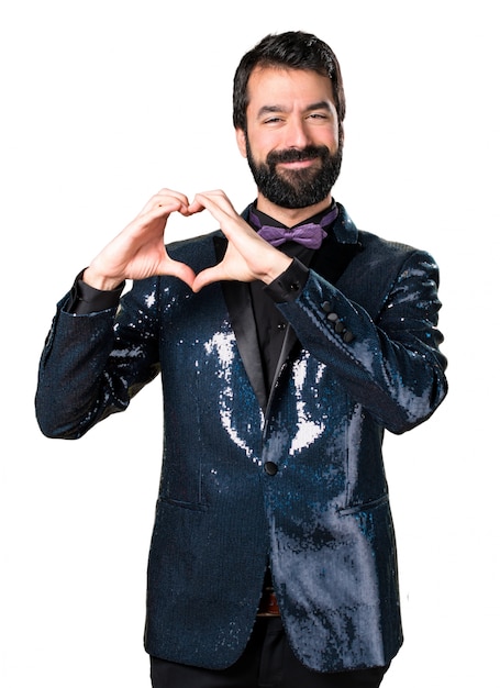 Hermoso hombre con chaqueta de lentejuelas haciendo un corazón con sus manos