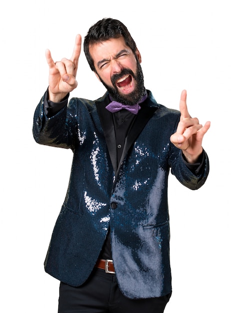 Foto gratuita hermoso hombre con chaqueta de lentejuelas haciendo gesto de cuerno