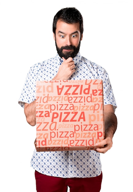 Foto gratuita hermoso hombre morena con barba sosteniendo una pizza