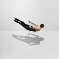 Foto gratuita hermoso joven atleta masculino practicando en estudio blanco con sombras en salto, aire volando