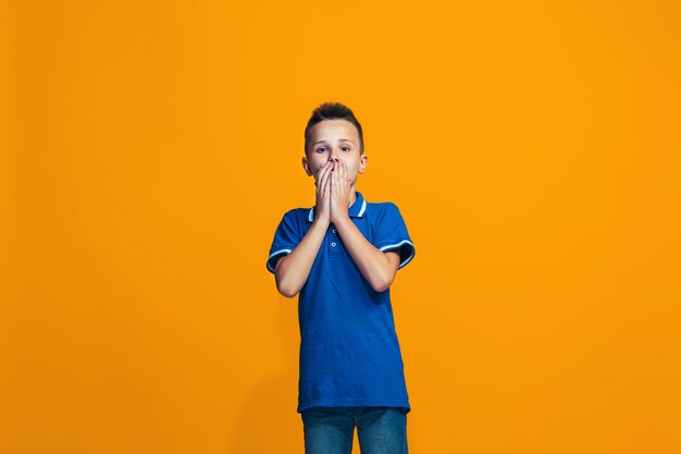 Hermoso muchacho adolescente mirando sorprendido aislado en naranja