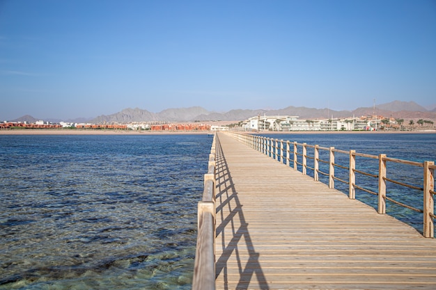 hermoso muelle largo de madera entre el mar y las montañas.