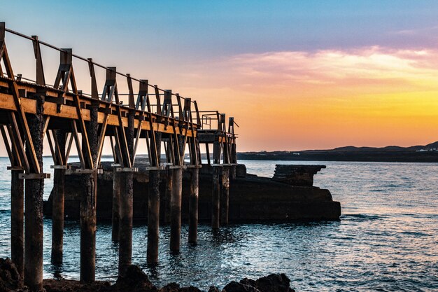 Hermoso muelle de madera en la costa del mar con una hermosa puesta de sol