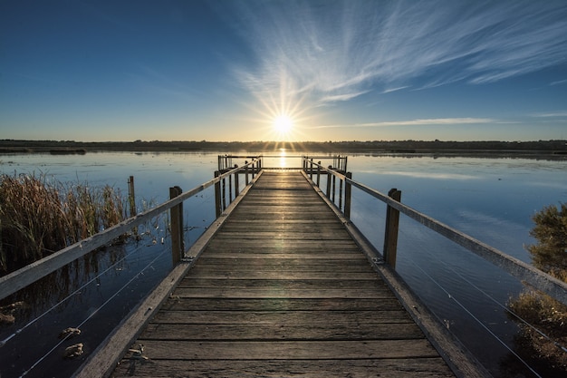 Foto gratuita hermoso muelle de madera junto al mar en calma con la hermosa puesta de sol sobre el horizonte