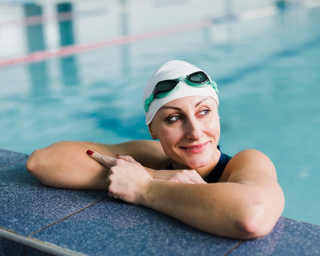 Mujer bonita con gorra de natación y gafas de natación en la piscina