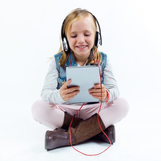 Hermoso niño escuchando música con tableta digital.