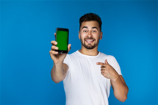 Hermoso niño sonríe y muestra algo en el teléfono a la cámara