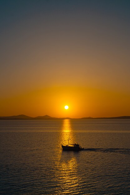 Hermoso océano con un pequeño bote flotando en el agua al atardecer