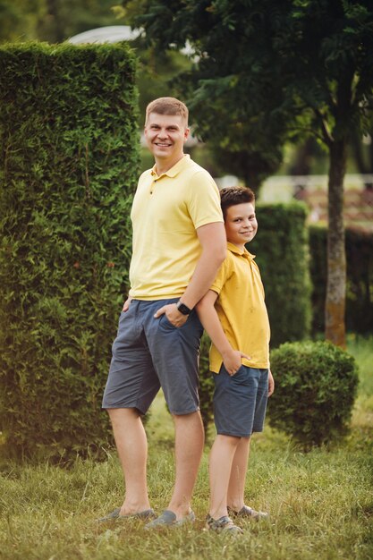 Hermoso padre caucásico posando para la cámara con su pequeño hijo en el parque en verano