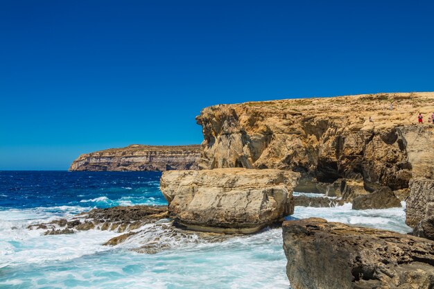 Hermoso paisaje de un acantilado rocoso cerca de las olas del mar bajo el hermoso cielo azul