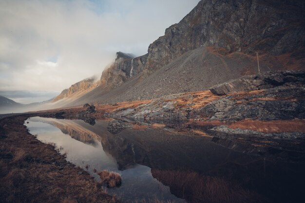 Hermoso paisaje de acantilados rocosos reflejados en un arroyo limpio en Islandia