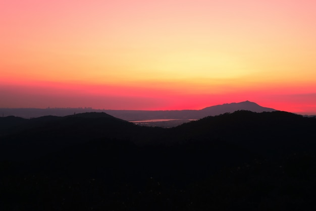 Hermoso paisaje de altas colinas cubiertas de hierba bajo el impresionante cielo del atardecer