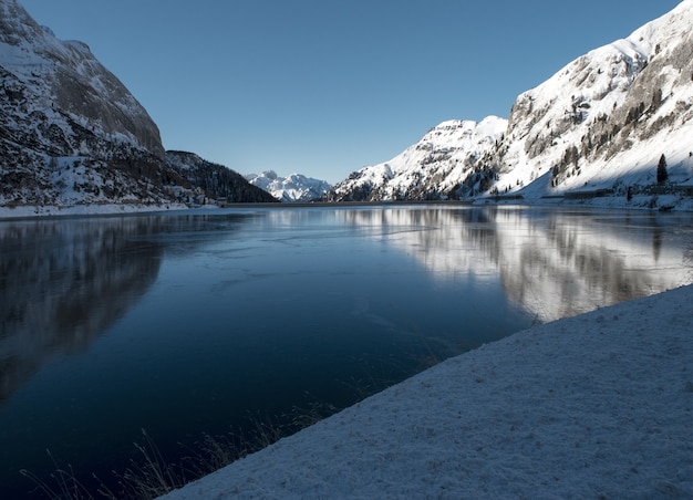 Hermoso paisaje de altas montañas cubiertas de nieve que se refleja en el lago en los Dolomitas