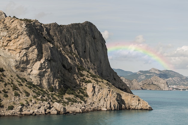 Hermoso paisaje con arco iris y roca.