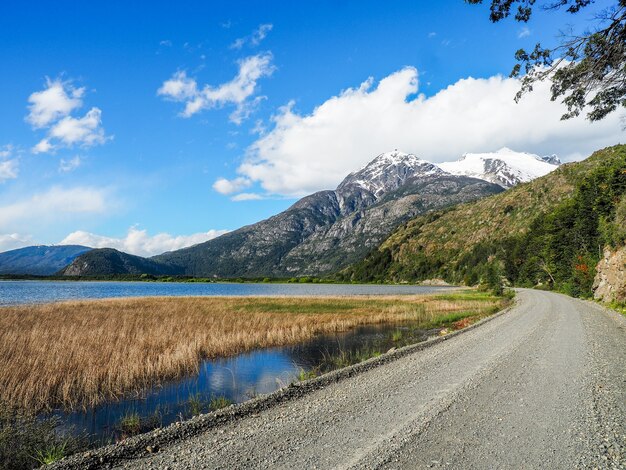 Hermoso paisaje de un camino rodeado de altas montañas rocosas y vegetación bajo un cielo nublado