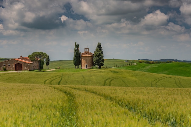 Foto gratuita hermoso paisaje de campos campestres rodeados de colinas bajo el cielo sombrío