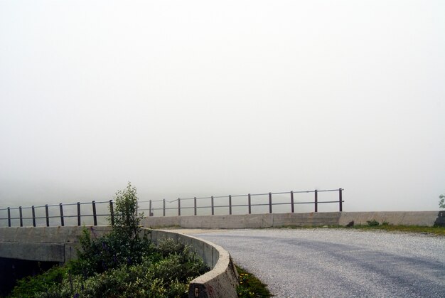 Hermoso paisaje de una carretera en un día sombrío con un fondo brumoso en Noruega