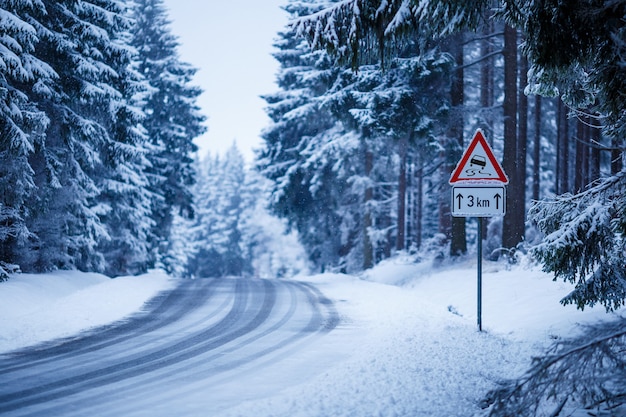 Hermoso paisaje de una carretera helada rodeada de abetos cubiertos de nieve.