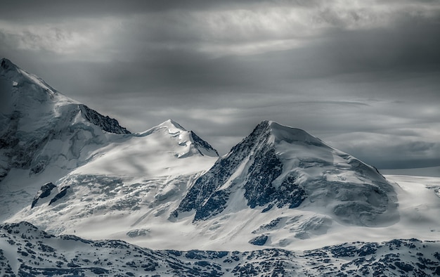 Hermoso paisaje de una cordillera cubierta de nieve bajo el cielo nublado