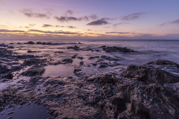 Hermoso paisaje de enormes formaciones rocosas cerca del mar bajo el impresionante cielo del atardecer