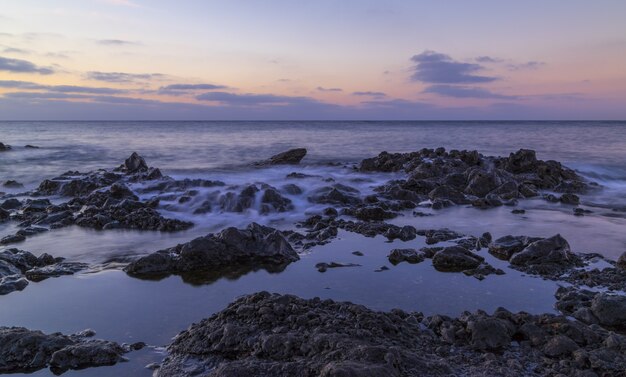 Hermoso paisaje de enormes formaciones rocosas cerca del mar bajo el impresionante cielo del atardecer