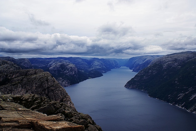 Hermoso paisaje de los famosos acantilados de Preikestolen cerca de un lago bajo un cielo nublado en Stavanger, Noruega