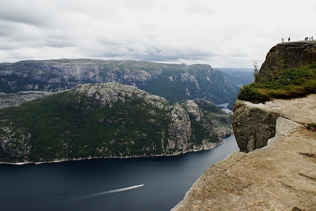 Foto gratuita hermoso paisaje de los famosos acantilados de preikestolen cerca de un lago bajo un cielo nublado en stavanger, noruega