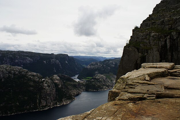 Hermoso paisaje de los famosos acantilados de Preikestolen cerca de un lago bajo un cielo nublado en Stavanger, Noruega