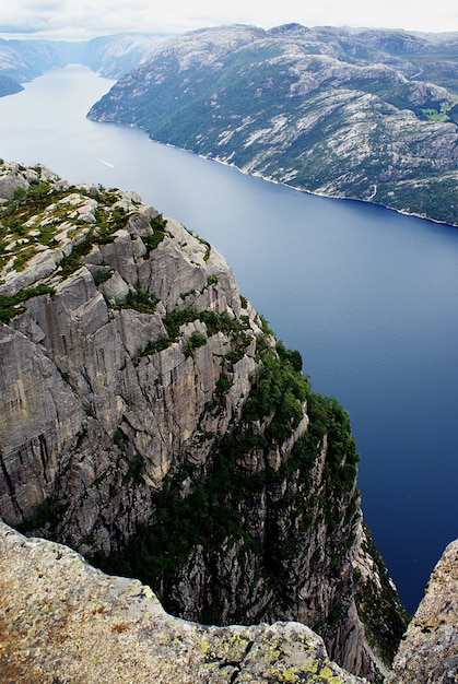 Hermoso paisaje de los famosos acantilados de Preikestolen cerca de un lago bajo un cielo nublado en Stavanger, Noruega