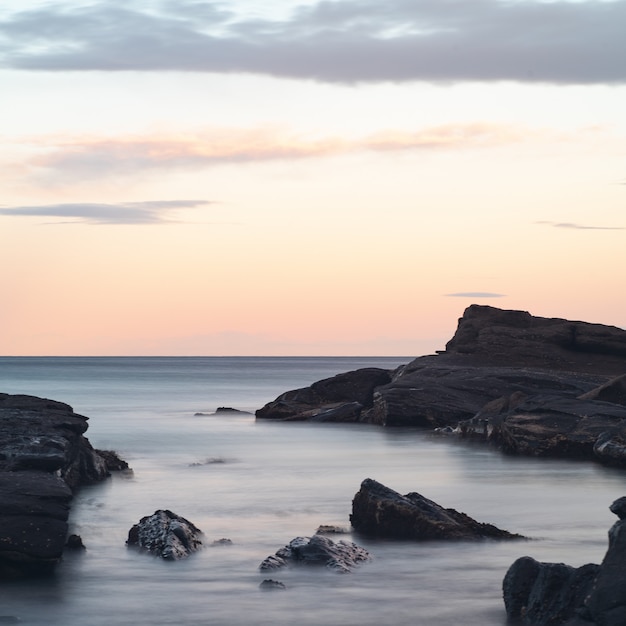 Foto gratuita hermoso paisaje de formaciones rocosas en el mar bajo el impresionante cielo colorido