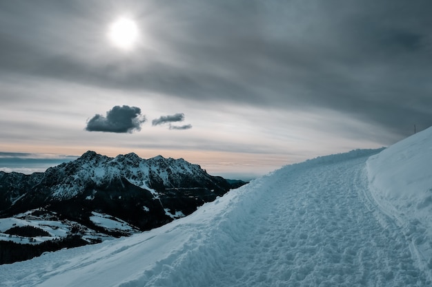 Hermoso paisaje invernal con un camino de nieve y una hermosa vista de las montañas cubiertas de nieve