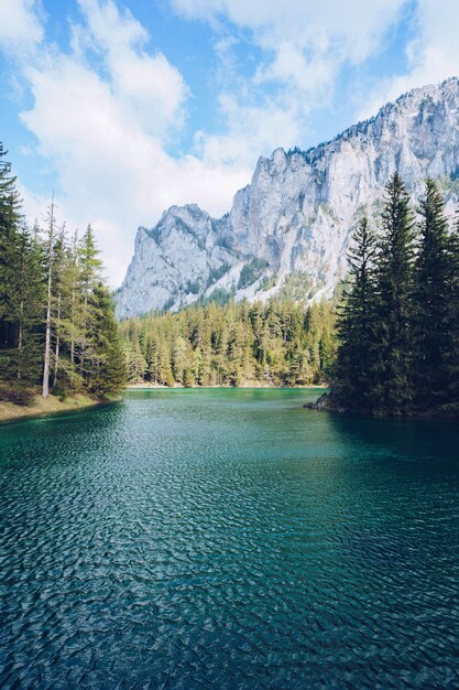 Hermoso paisaje con un lago en un bosque y sorprendentes altas montañas rocosas