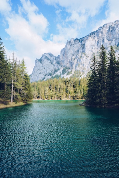 Hermoso paisaje con un lago en un bosque y sorprendentes altas montañas rocosas