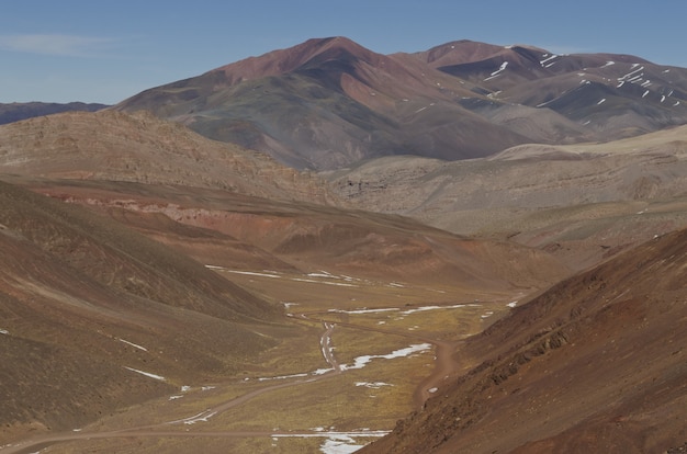 Hermoso paisaje montañoso parcialmente cubierto de nieve bajo un cielo brillante