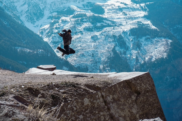 Hermoso paisaje de una mujer saltando en la cima de una montaña rocosa en el punto de suicidio en Kalpa