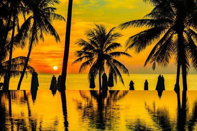 Hermoso paisaje de naturaleza al aire libre con mar oceánico y palmera de coco alrededor de la piscina en Sunrsie o atardecer